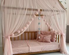 a pink canopy bed with white curtains and pillows