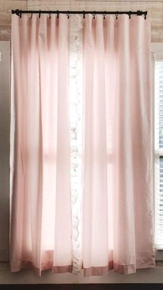 a pink curtain hanging in front of a window