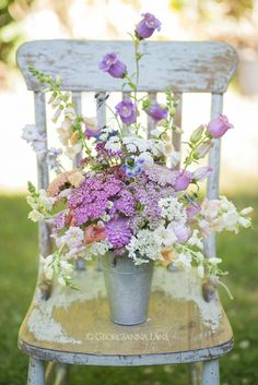 an old chair with flowers in it sitting on the grass