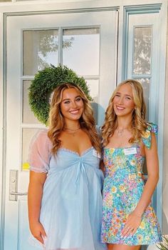 two beautiful young women standing next to each other in front of a door with potted plants