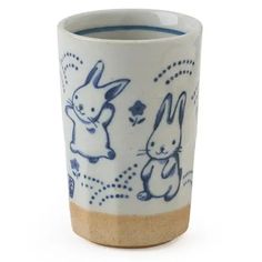 a blue and white coffee cup with rabbits on the side, sitting in front of a white background