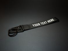 a black lanyard with white text on it and a pair of scissors in the foreground