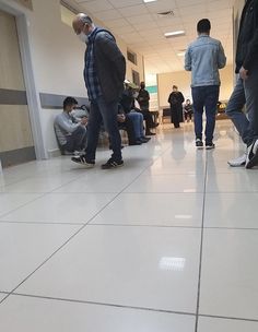 several people are standing and sitting in an office building with their feet on the floor