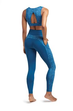 a woman in blue sports bra top and leggings, looking back at the camera