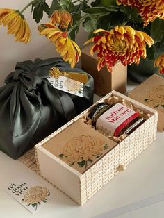 an open box with some items inside on a table next to flowers and other decorations