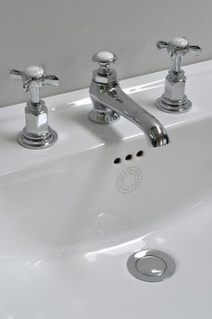 two chrome faucets on a white sink in a bathroom