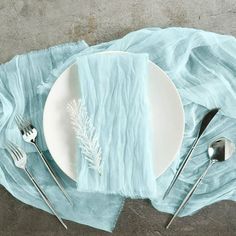 an empty plate and silverware on a blue table cloth