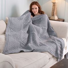 a woman sitting on a couch under a blanket