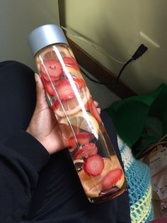 a person holding a water bottle with strawberries in it