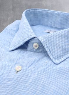 Inspired by the effortless style worn in Portofino, the Alexander in Light Blue Gingham Linen is a must-have of any wardrobe. Crafted of super soft linen fabric, it exudes effortless style when worn untucked. The pale purple stitching on the top collar button and cuffs adds a polished finishing touch. Worn under a suit and with a tie, the shirt exudes casual ease. The Alexander is the trimmest of all our fits, calibrated to accentuate a lean, athletic body type. • Trimmest Fit • 100% Linen • Spr Spring Plaid Linen Shirt, Classic Plaid Linen Shirt, Light Blue Linen Button-up Shirt, Blue Linen Shirt With Placket, Blue Linen Tops For Business Casual, Spring Linen Business Tops, Spring Business Linen Tops, Blue Linen Shirt For Daywear, Spring Gingham Shirt With Spread Collar