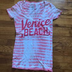 V-Neck Venice Beach American Eagle Shirt. Pink And White Design. Never Worn. V-neck T-shirt For Summer Vacation, Trendy V-neck T-shirt For Vacation, Summer V-neck Graphic Print Top, Summer Vacation V-neck T-shirt, Graphic Print V-neck Tops For Vacation, V-neck Graphic Print T-shirt For Vacation, V-neck Cotton T-shirt For The Beach, Summer V-neck T-shirt For Vacation, Casual V-neck T-shirt For Vacation