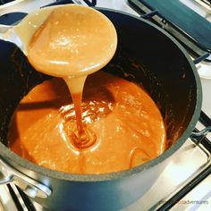 sauce being poured into a pot on the stove