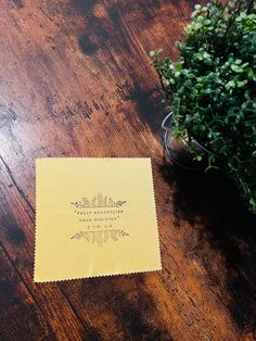 a napkin sitting on top of a wooden table next to a potted green plant