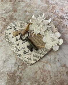 a paper heart with flowers and a key attached to it