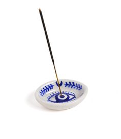 a small bowl with an eye painted on it and a toothpick in the middle