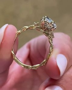 a close up of a person's hand holding a ring with a flower on it