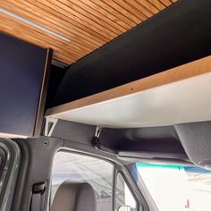 the interior of a vehicle with wood paneling on the ceiling and televisions above it