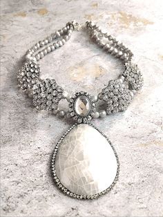 This stunning bridal piece makes a gorgeous regal statement! Beautiful glass crystal settings glimmer with brilliance while this cream white shell pendant coupled with light gray freshwater pearls add a soft chic touch! Necklace also includes extender chain so as to adjust to desired length.Product Details.Semi precious cream white shell pendant..Freshwater light grey pearls..Silver plated glass crystal settings..Antique silver plated caps..Silver plated brass end clamps..Silver filled jump ring Kay Adams, Bridal Accessory, Necklace Elegant, Pinterest Group, Pearl Grey, Shell Pendant, Gorgeous Necklaces, The Cream, Silver Pearls