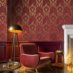 a living room with red and gold wallpaper, two chairs, a coffee table and a fireplace