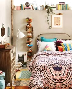 a bed room with a neatly made bed and lots of books on the shelves above it