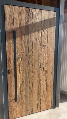 a close up of a wooden door with metal handle on concrete floor next to building