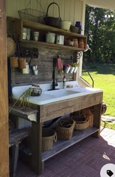 a sink sitting under a wooden structure on top of a brick floor next to a green field