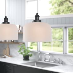 two lights hanging over a sink in a kitchen