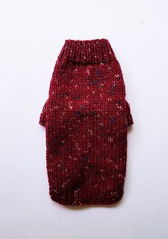 a red knitted dog sweater laying on top of a white surface