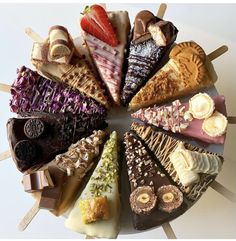 an assortment of desserts arranged in a circle on sticks with chocolate, strawberries and other toppings