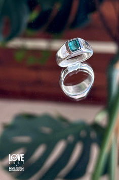 Deep teal tourmaline set in a handmade sterling silver setting on a mirrored surface reflecting a large green leaf. Silver Tourmaline Promise Ring, Silver Emerald Cut Tourmaline Jewelry, Silver Tourmaline Birthstone Ring With Gemstone, Modern Sterling Silver Emerald Ring, Turquoise Sapphire Gemstone Ring In Sterling Silver, Turquoise Sapphire Ring In Sterling Silver, Turquoise Sapphire Ring With Sterling Silver, Silver Emerald Ring With Tourmaline Birthstone, Silver Emerald Cut Tourmaline Ring