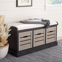 a white and black bench sitting next to a potted plant on top of a rug