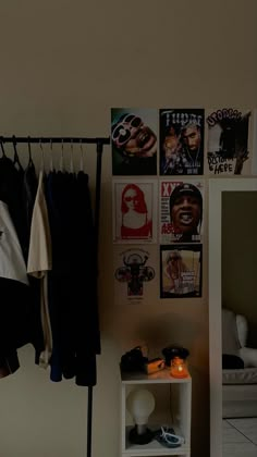 a room with clothes hanging on the wall and posters on the wall next to it