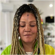 a woman with long braids and piercing on her nose looking down at the camera