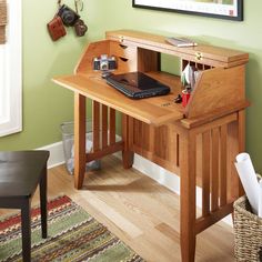 a wooden desk with a laptop on top of it in front of a green wall