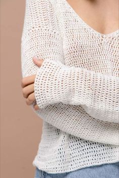 a close up of a person wearing a white sweater and jeans with her arms crossed