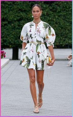 a model walks down the runway in a white floral print romper and matching sandals