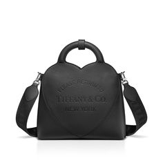 Inspired by one of the House’s most distinctive designs, the heart-shaped Return to Tiffany® handbags are crafted in supple leather that nod to our iconic jewelry. This small tote adds a playful touch to every day. It’s embossed with our signature heart motif and designed with a detachable woven strap, while an interior zip pocket keeps essentials organized. Black Taurillon leather; 11.4 x 13.7 x 4.3"; Detachable woven strap and fixed handles; Interior zip pocket; Flap closure with magnet; Cotton-blend lining; Comes with dust bag; Made in Italy | Return to Tiffany® Small Tote Bag in Black Leather Iconic Jewelry, Accessory Inspo, Return To Tiffany, Dressy Shorts, Leather Tote Bags, Heart Motif, Classic Handbags, Small Tote Bag, Tote Bag Leather