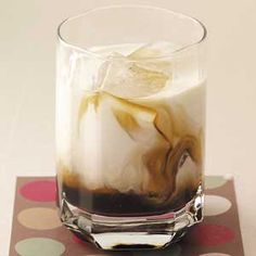 a glass filled with liquid sitting on top of a polka dot tablecloth covered coaster