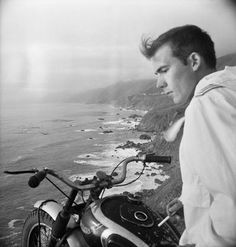 a man sitting on top of a motorcycle next to the ocean with an inspirational quote