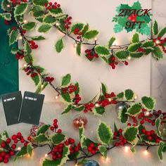 holly garland with red berries and green leaves next to two small christmas ornaments on a table