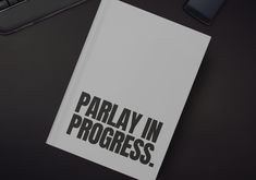 there is a book that says parlay in progress next to a phone and keyboard