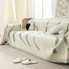 a living room with a white couch covered in a green and black striped blanket next to two slippers on the floor