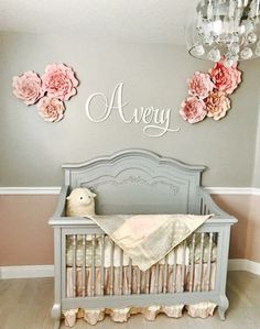 a baby crib with pink flowers on the wall and a chandelier above it