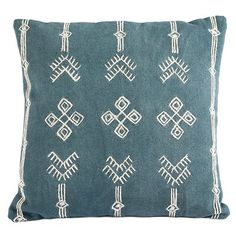 a blue pillow with white embroidered designs on it