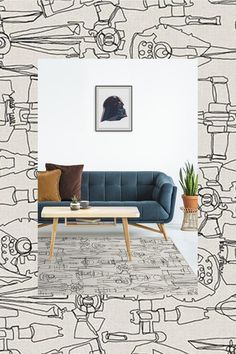 a blue couch sitting in front of a white wall with drawings on the walls behind it