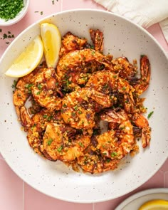 a white bowl filled with cooked shrimp and garnished with parsley on the side