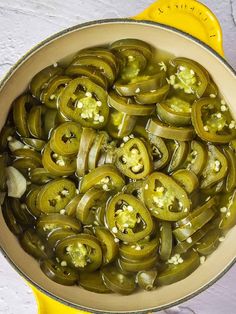 a pot filled with pickles and onions sitting on top of a counter next to a yellow spatula