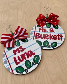 two personalized christmas ornament hanging on a wooden table with red bows and polka dots