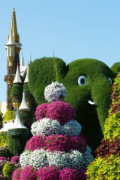 an elephant made out of flowers in front of a building with a castle on top