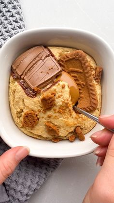 a person holding a spoon in a bowl with peanut butter and ice cream on it